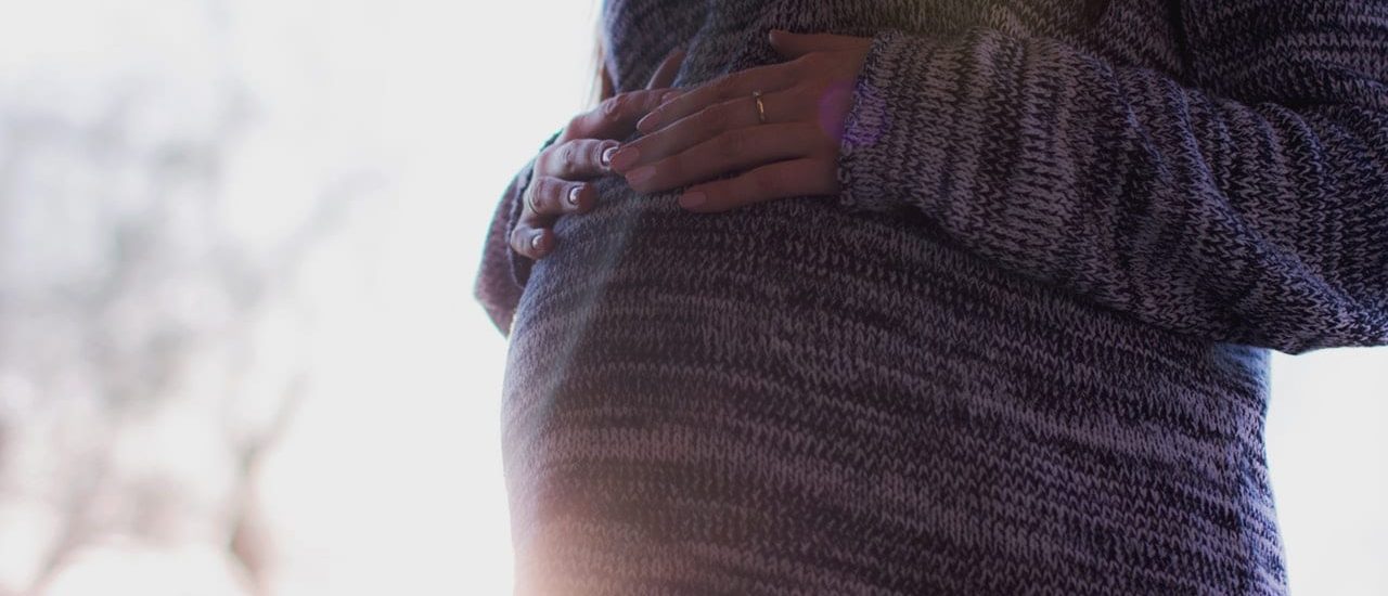 A pregnant woman in a gray sweater